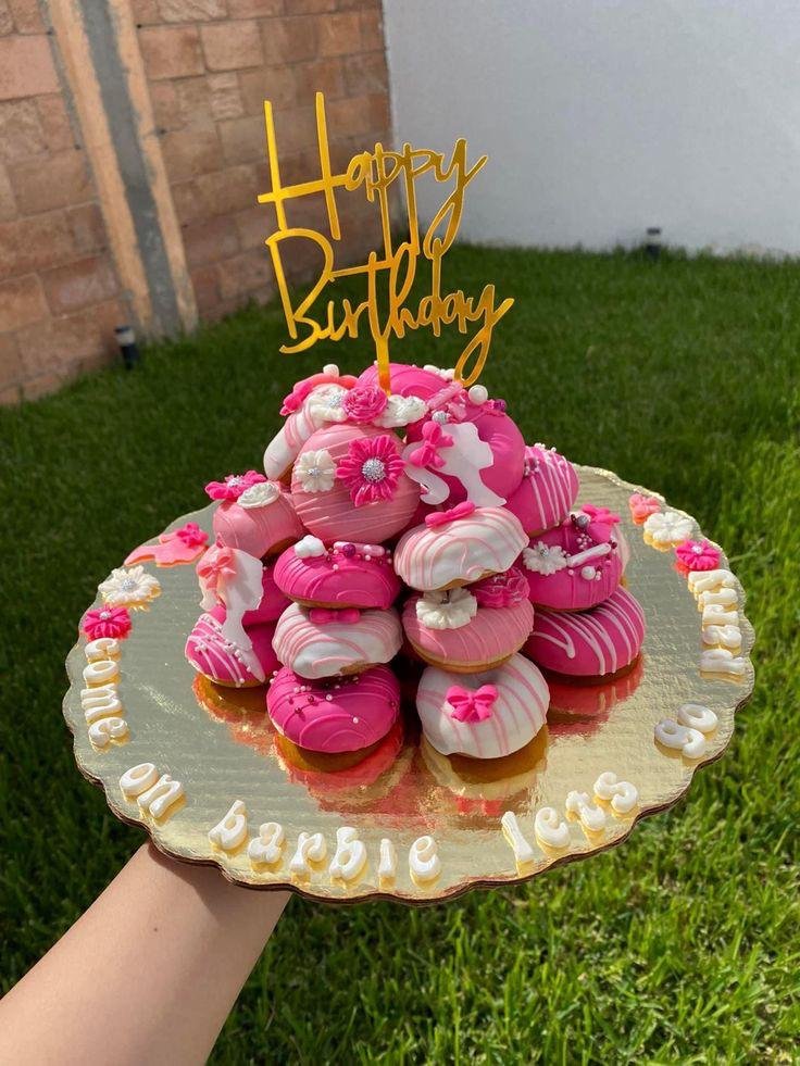 Donuts no lugar do bolo para uma festa de aniversário. Donuts com decoração rosa, vela escrito "Happy Birthday".
