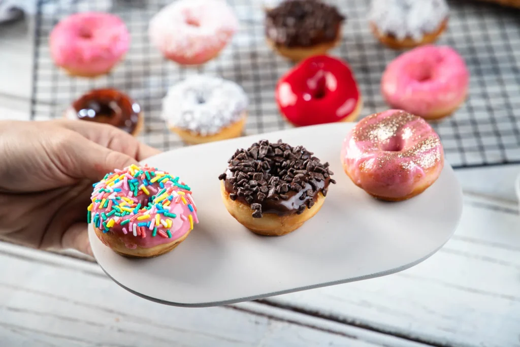 Mini donuts congelados: alternativa perfeita para quiosques e parques 2 Mini donuts, tres unidades enfileiradas em um prato branco.