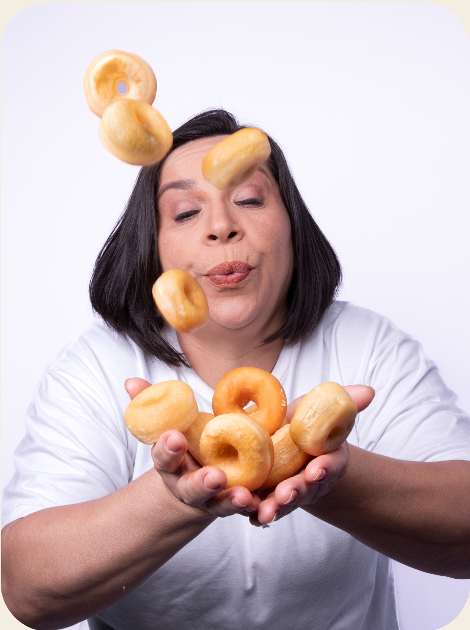 Mulher com cabelos escuros assoprando mini donuts.
