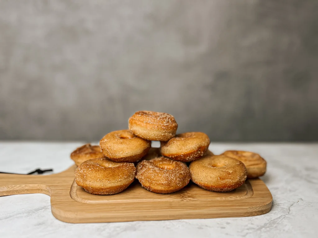 Mini donuts com canela e acucar e uma tábua marrom.